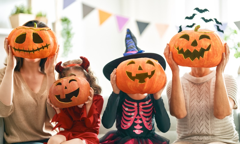 Halloween photography of four children holding pumpkins in front of faces